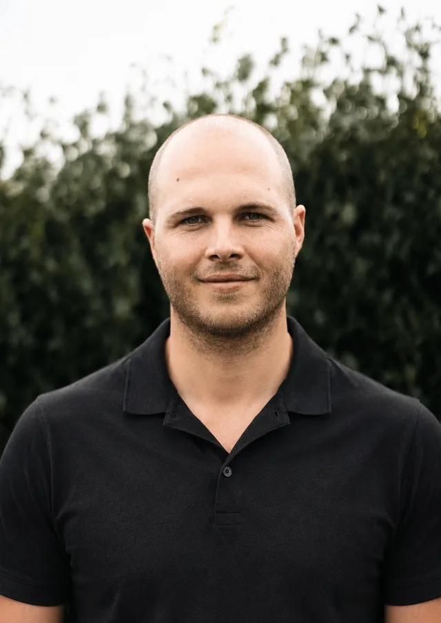 Ben Sawkins, standing in front of a hedge in a dark polo shirt.